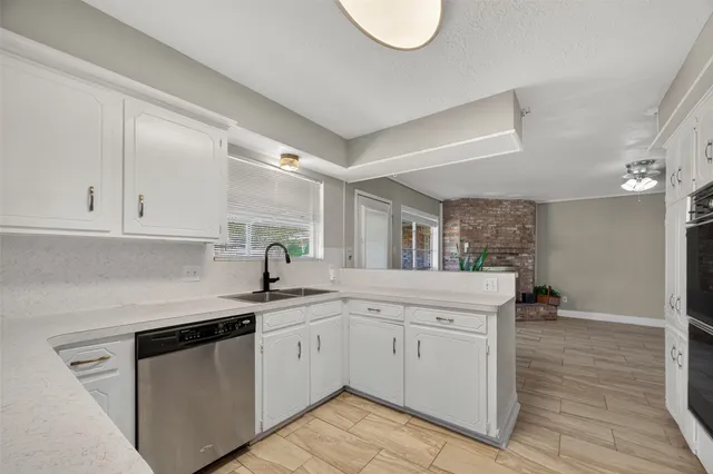 a kitchen with a sink dishwasher and white cabinets with wooden floor