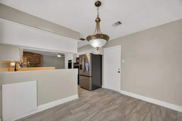 a view of a kitchen with a refrigerator a ceiling fan and a wooden floor
