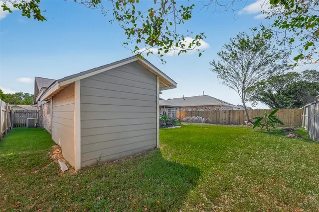 a backyard of a house with plants and large tree