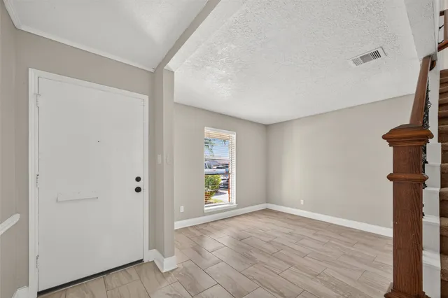 a view of an empty room with window and wooden floor