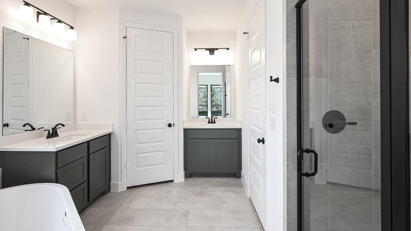 175 High Rock Pass Kyle, TX 78640 - Photo 15 of 39 Full bath with a stall shower, two vanities, a freestanding bath, and light tile patterned flooring