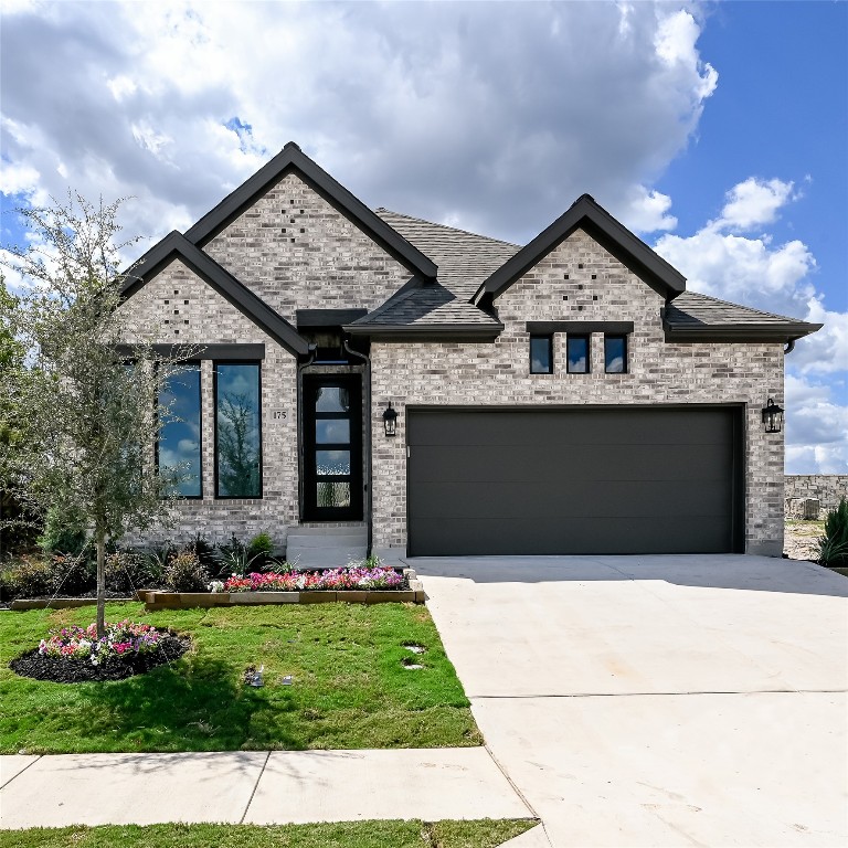 175 High Rock Pass Kyle, TX 78640 - Photo 2 of 39 View of front of home featuring driveway, an attached garage, brick siding, a front lawn, and a shingled roof