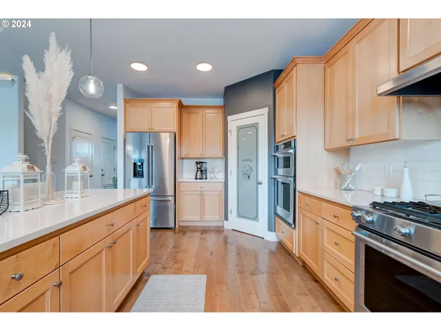 a large kitchen with cabinets wooden floor and stainless steel appliances