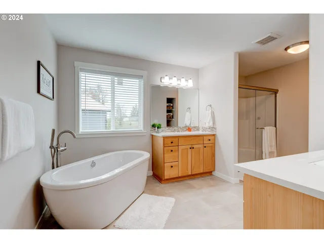a bathroom with a tub a sink a mirror and a window