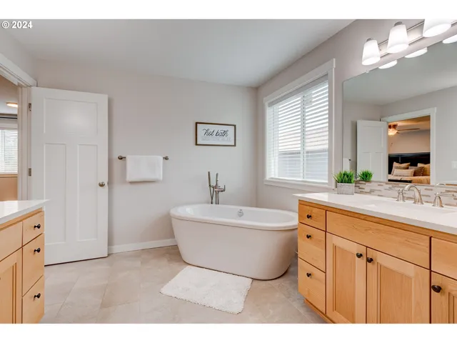 a spacious bathroom with a double vanity sink a mirror a bathtub and next to a window