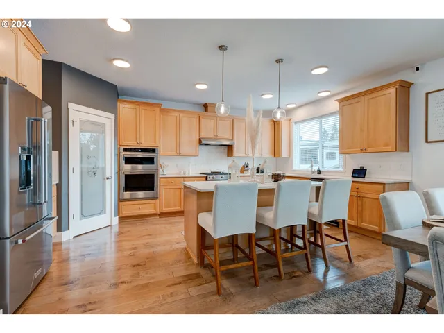 a kitchen with stainless steel appliances kitchen island granite countertop a refrigerator a stove a sink dishwasher with a dining table and chairs