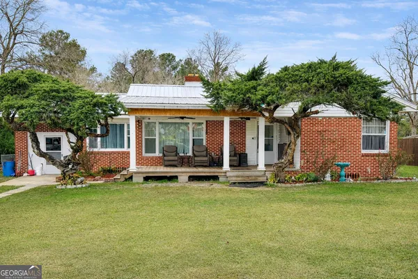 a front view of a house with a garden and trees