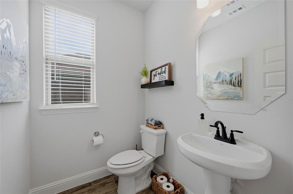 864 Shadow Valley Road Whitesboro, TX 76273 - Photo 29 of 40 Pedestal sink with matte black faucet, wall-mounted octagonal mirror, and wood-finish flooring