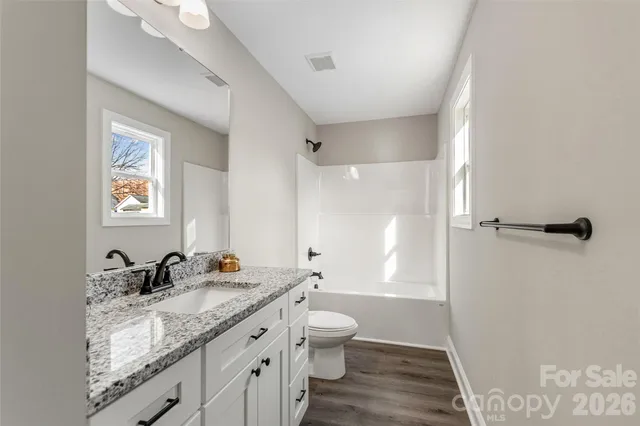 a bathroom with a granite countertop sink a toilet a shower and a mirror