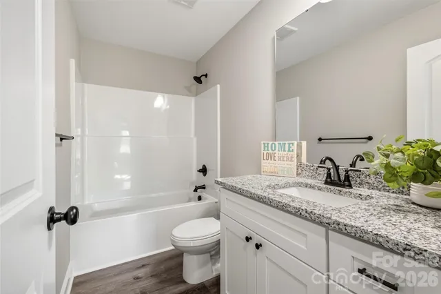 a bathroom with a granite countertop sink a toilet a mirror and shower