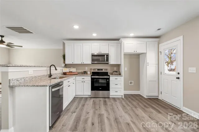 a kitchen with granite countertop a sink stove and refrigerator