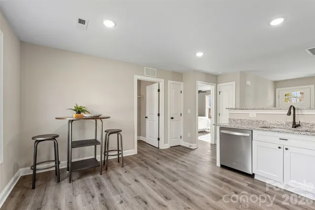 a living room with stainless steel appliances granite countertop furniture wooden floor and a kitchen view