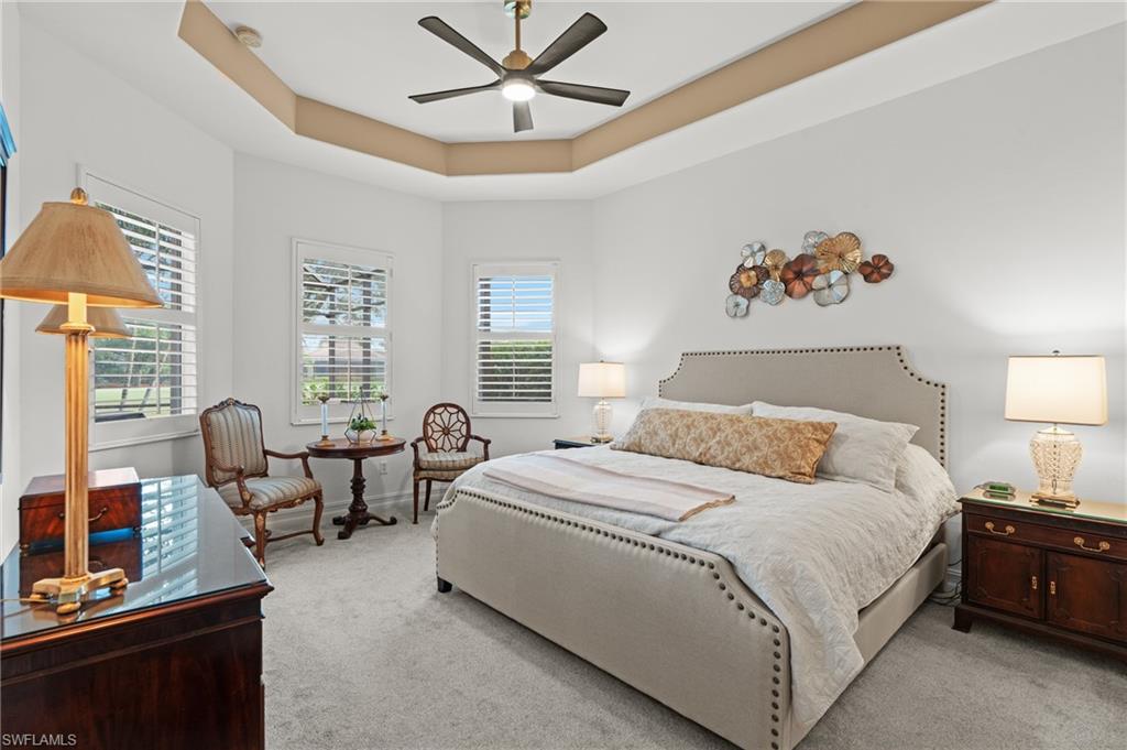 7806 Ashton Road Naples, FL 34113 - Photo 11 of 27 Bedroom featuring a tray ceiling, multiple windows, ceiling fan, and light carpet