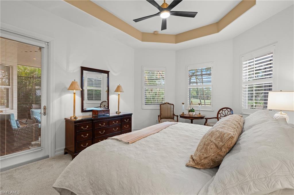 7806 Ashton Road Naples, FL 34113 - Photo 12 of 27 Bedroom with multiple windows, a tray ceiling, carpet, and ceiling fan