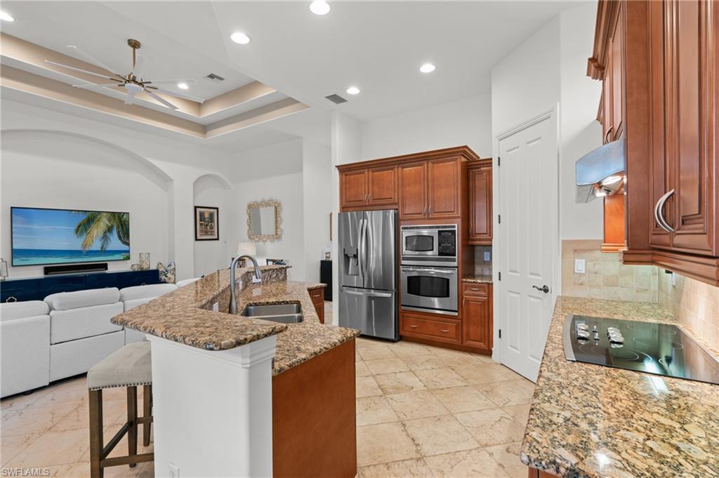 7806 Ashton Road Naples, FL 34113 - Photo 27 of 27 Kitchen with backsplash, a sink, a breakfast bar, open floor plan, and stainless steel appliances