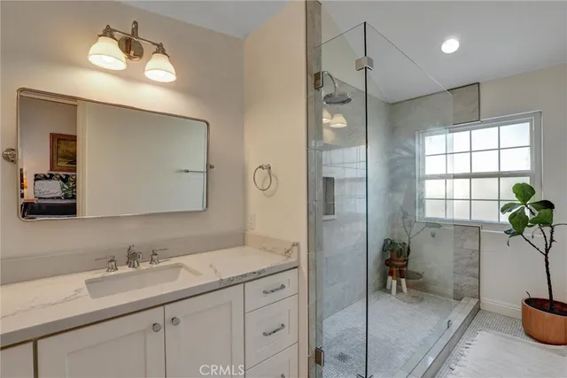 a bathroom with a granite countertop sink a mirror a vanity and a shower