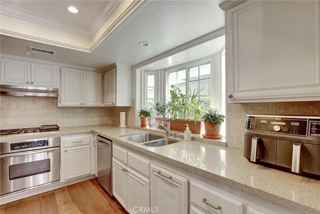 a kitchen with stainless steel appliances white cabinets and a stove top oven