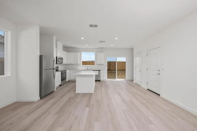 a open kitchen with white cabinets and wooden floor