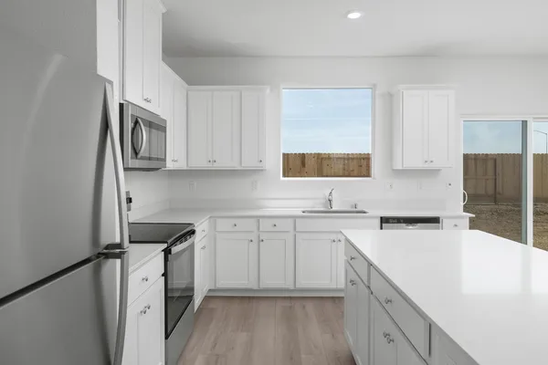 a kitchen with cabinets appliances a sink and a window