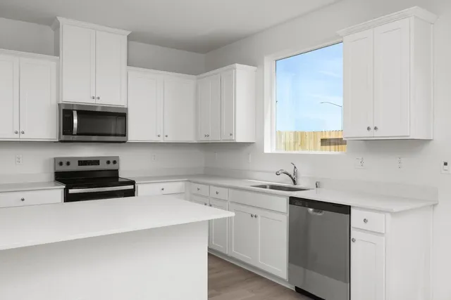 a kitchen with stainless steel appliances granite countertop white cabinets sink and window
