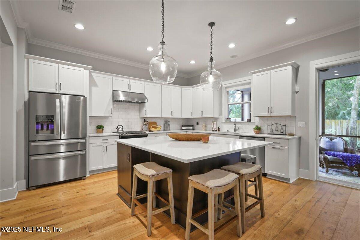740 Paradise Lane Atlantic Beach, FL 32233 - Photo 13 of 38 a kitchen with stainless steel appliances granite countertop a refrigerator a sink dishwasher a stove and white cabinets with wooden floor