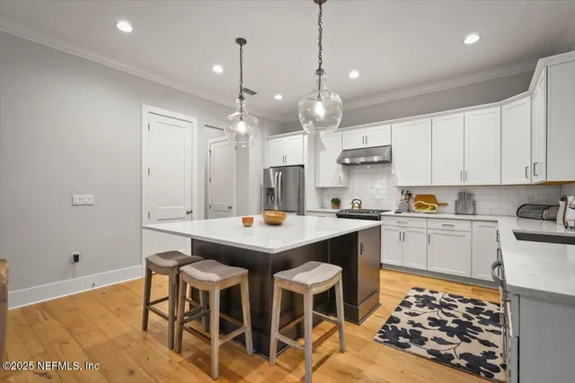 a kitchen with a stove a refrigerator a sink dishwasher with a dining table and chairs with wooden floor