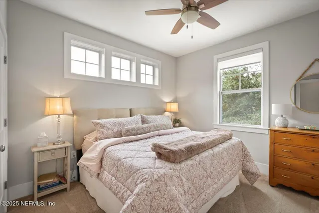a spacious bedroom with a bed a couch and a chandelier fan