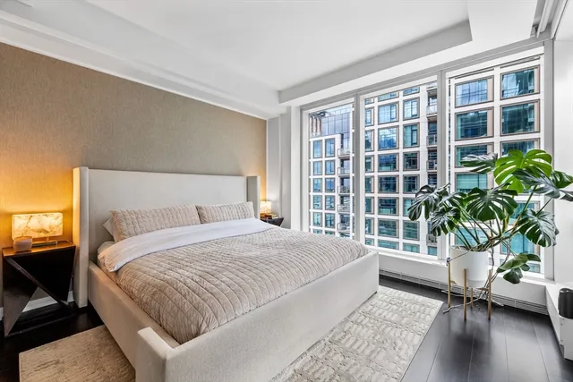 a bedroom with a large bed and a potted plant in front of it