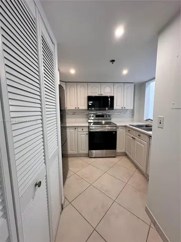 a kitchen with white cabinets stainless steel appliances and a sink