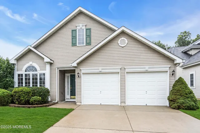 a view of a white house next to a yard and large trees