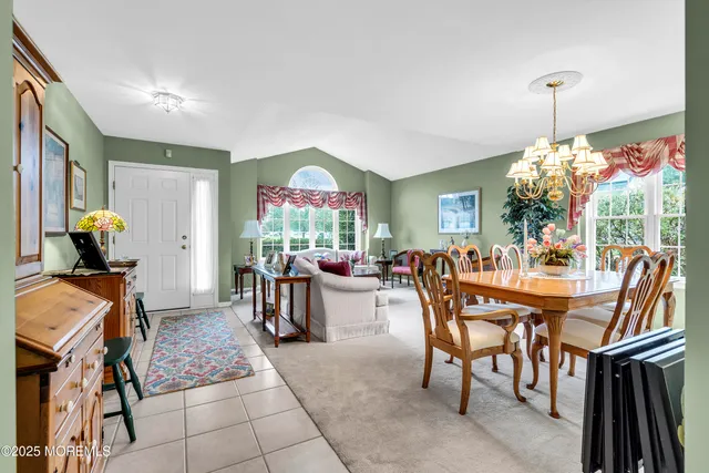a view of a dining room and livingroom with furniture wooden floor a chandelier