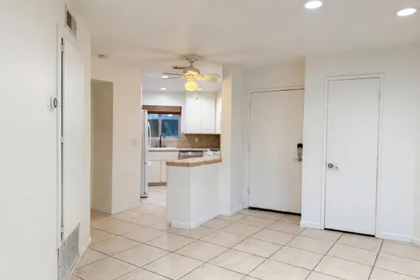 a view of a kitchen with a sink and dishwasher a refrigerator with white cabinets