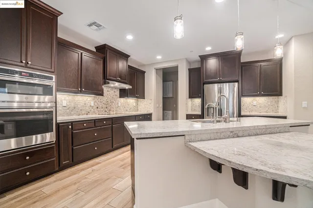 a kitchen with kitchen island granite countertop wooden cabinets a refrigerator and a sink