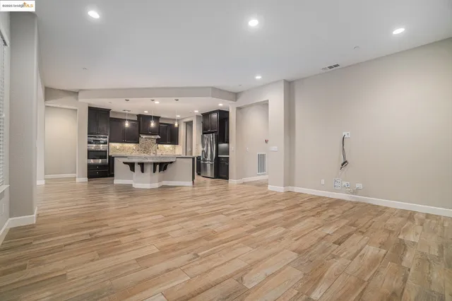 a view of a living room a kitchen island wooden floor and a fireplace