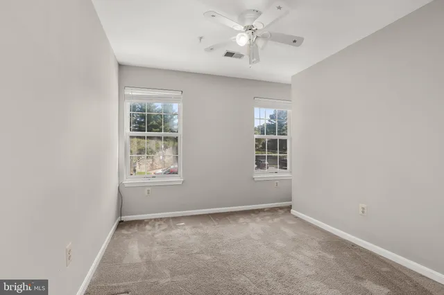 an empty room with windows and ceiling fan