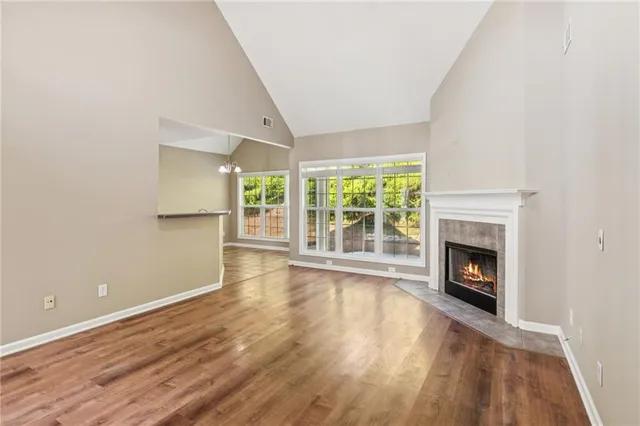 an empty room with wooden floor fireplace and windows