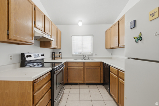 7910 Woolley Way Magna, UT 84044 - Photo 7 of 26 U-shaped kitchen featuring wood cabinetry, light-toned countertops, and tile flooring