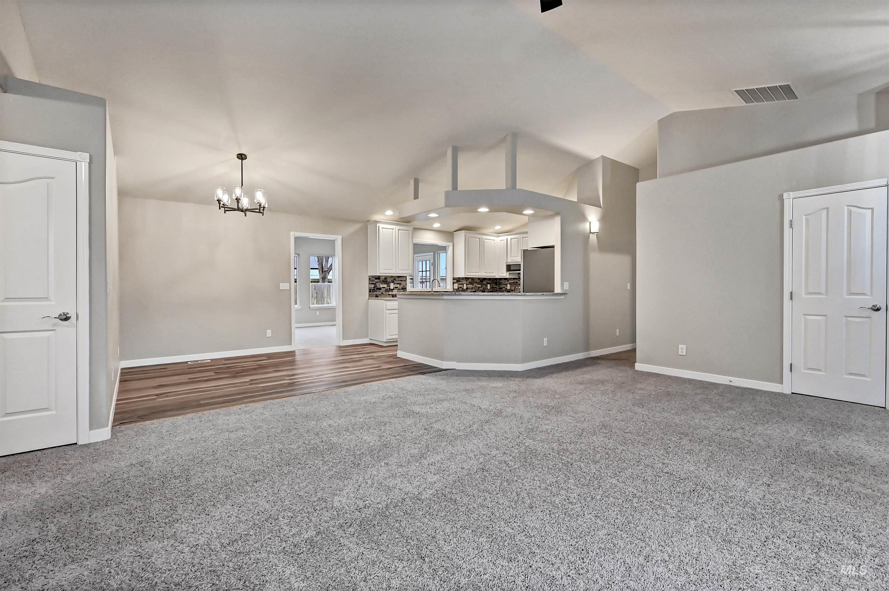 366 West Harris Street Meridian, ID 83642 - Photo 12 of 31 Unfurnished living room with dark carpet, a chandelier, and high vaulted ceiling