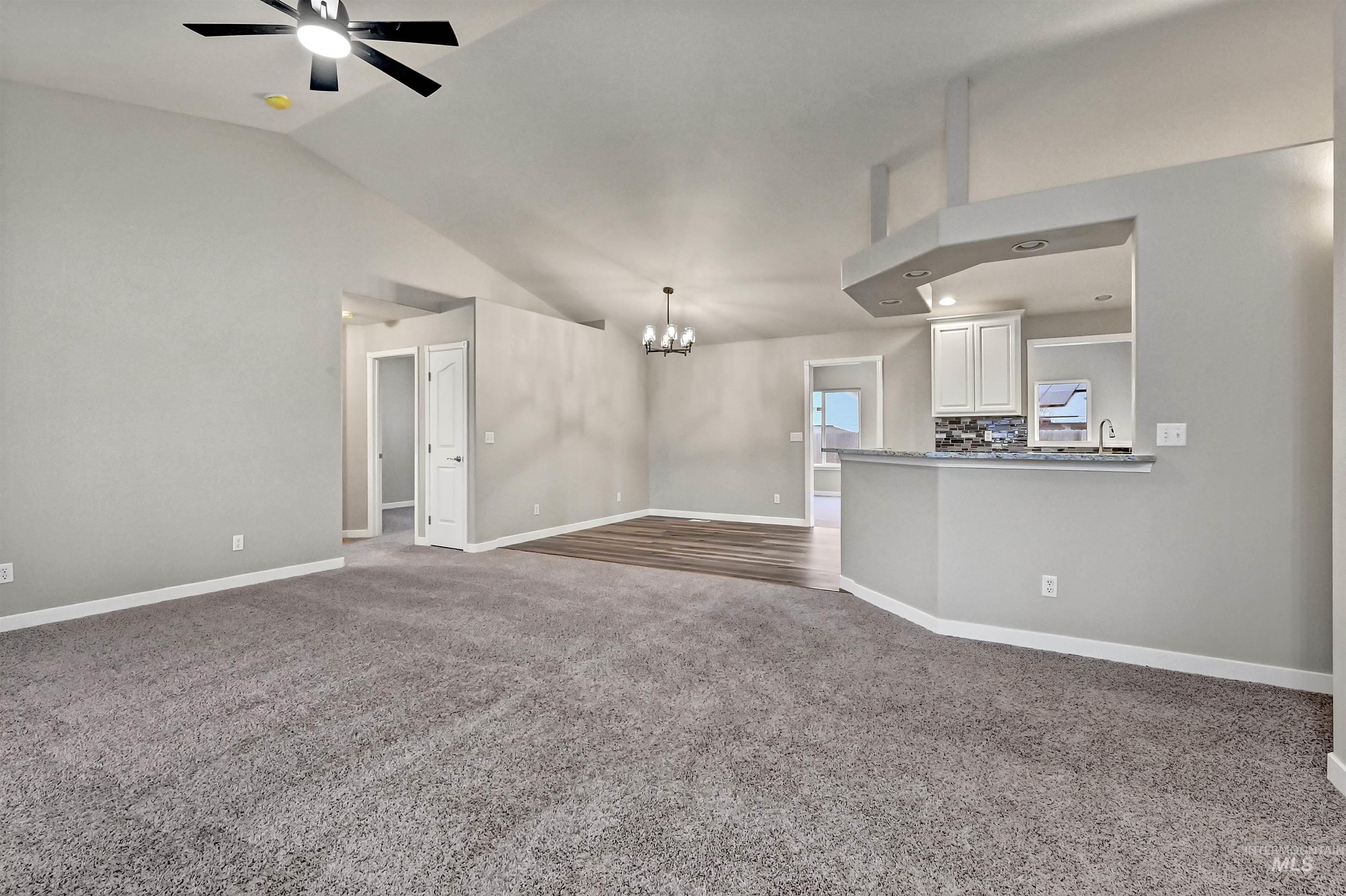 366 West Harris Street Meridian, ID 83642 - Photo 5 of 31 Unfurnished living room with a chandelier, dark colored carpet, vaulted ceiling, and a ceiling fan