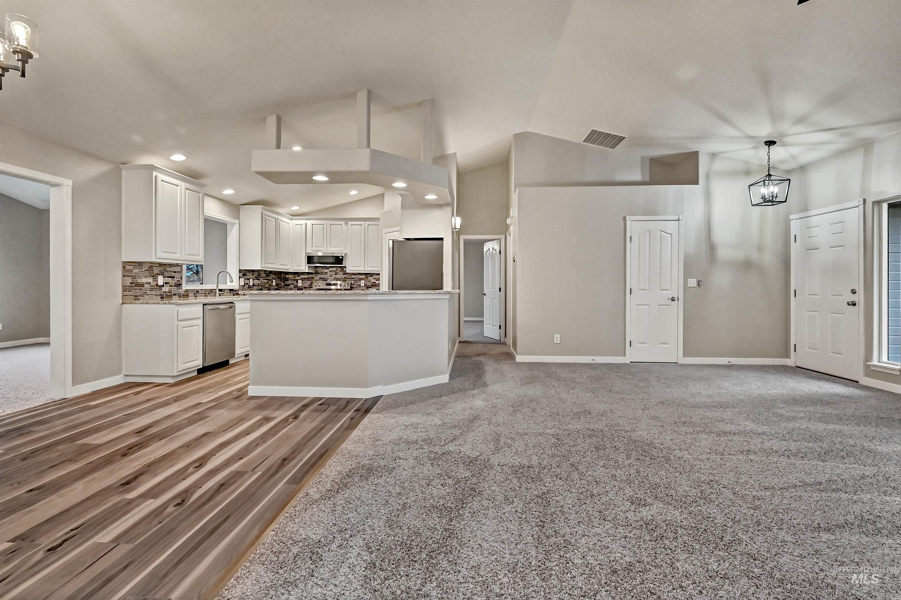 366 West Harris Street Meridian, ID 83642 - Photo 30 of 31 Kitchen featuring white cabinets, decorative backsplash, open floor plan, stainless steel appliances, and high vaulted ceiling