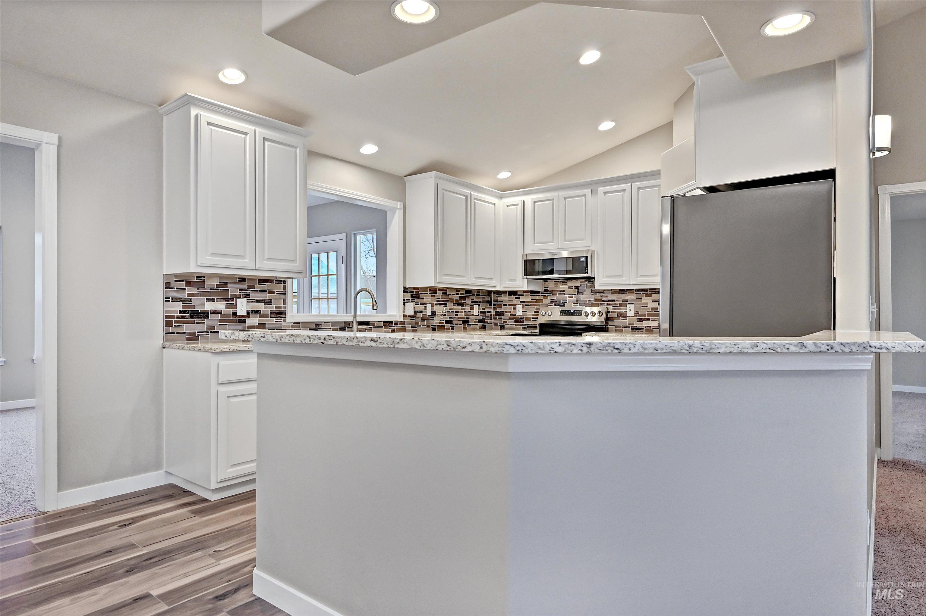 366 West Harris Street Meridian, ID 83642 - Photo 6 of 31 Kitchen featuring light stone countertops, white cabinetry, appliances with stainless steel finishes, decorative backsplash, and lofted ceiling