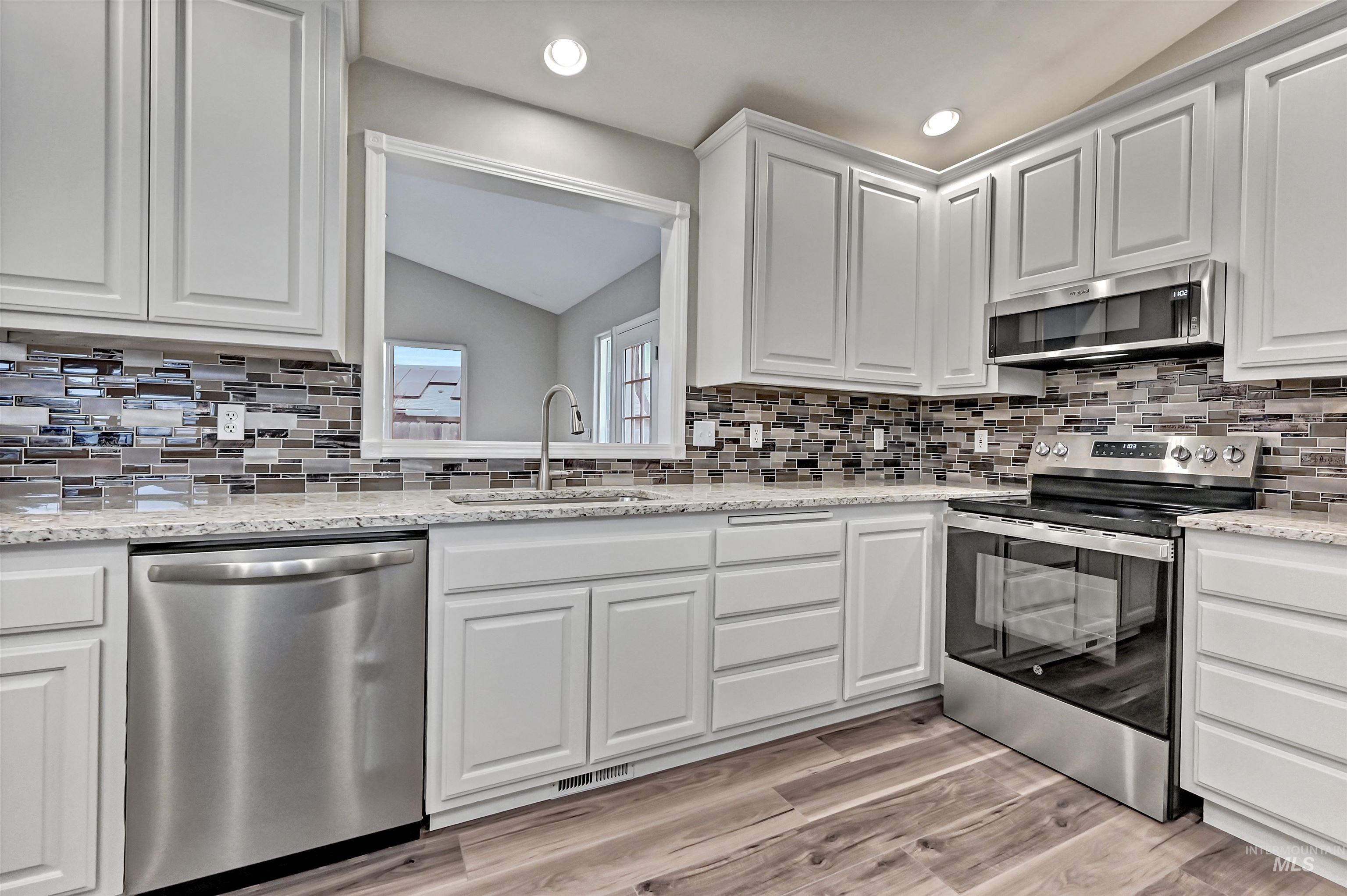366 West Harris Street Meridian, ID 83642 - Photo 7 of 31 Kitchen with stainless steel appliances, white cabinetry, lofted ceiling, light stone countertops, and light wood-style flooring