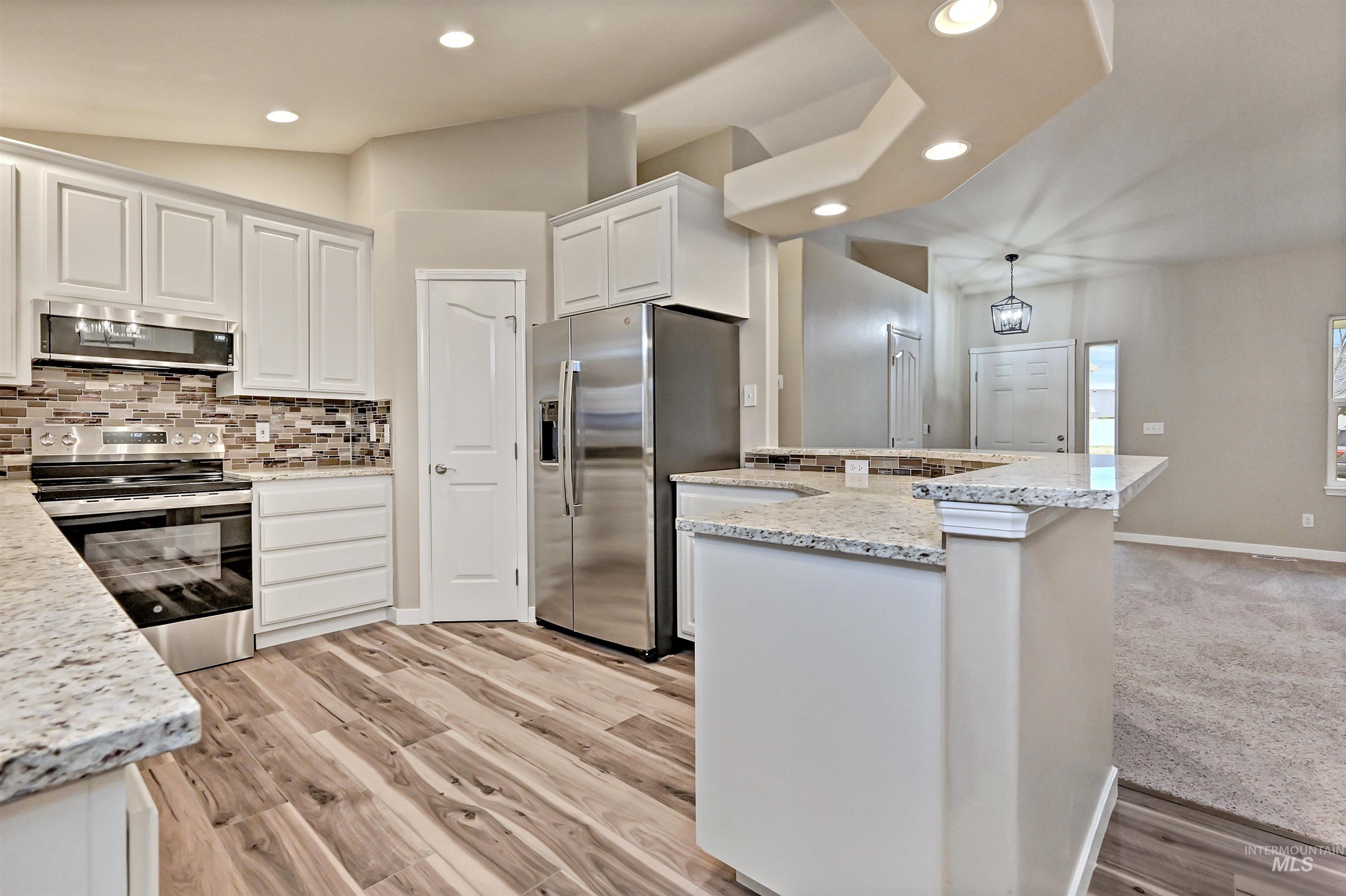 366 West Harris Street Meridian, ID 83642 - Photo 8 of 31 Kitchen featuring stainless steel appliances, vaulted ceiling, white cabinets, light stone counters, and decorative backsplash