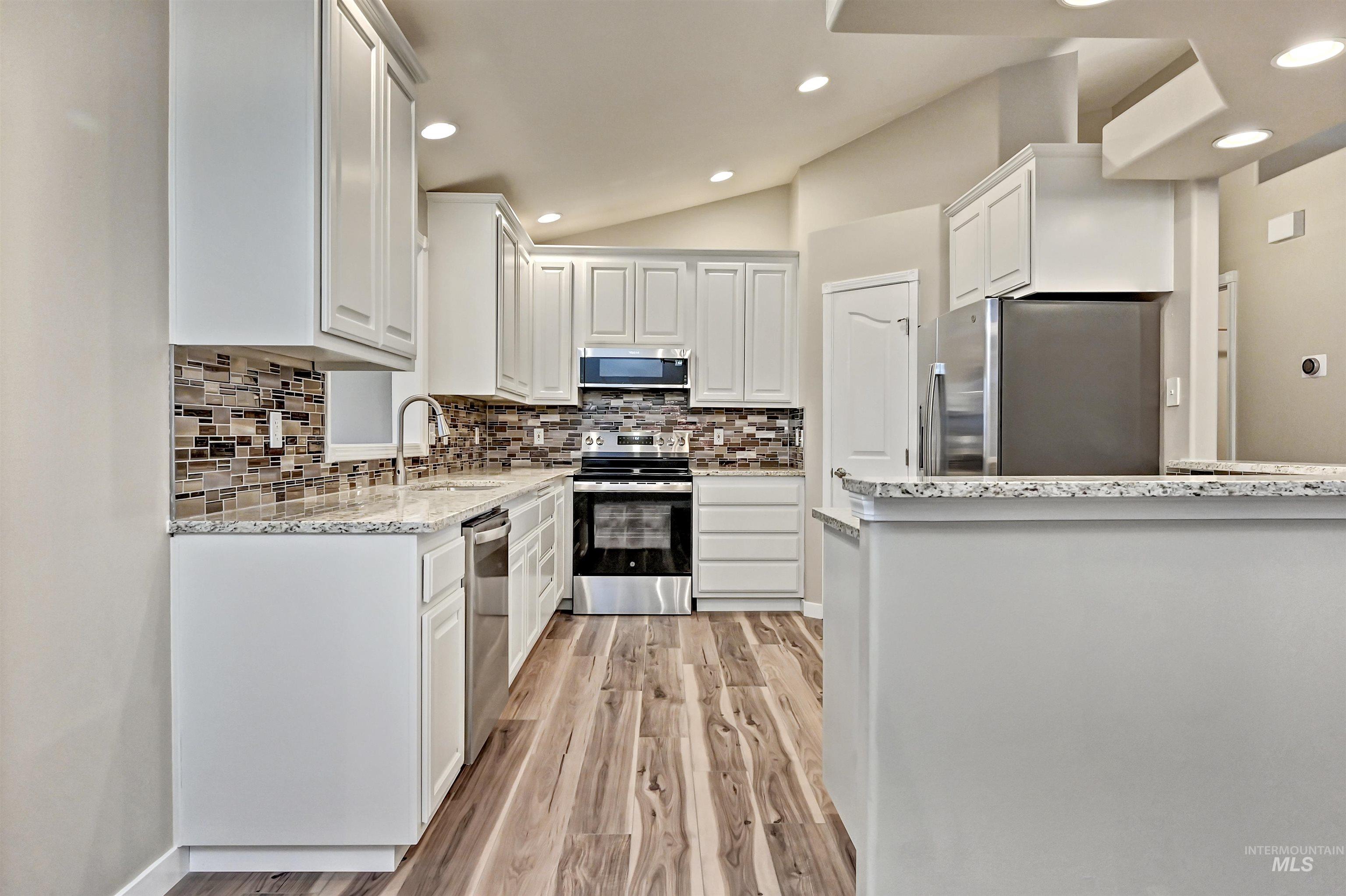 366 West Harris Street Meridian, ID 83642 - Photo 9 of 31 Kitchen featuring light stone countertops, vaulted ceiling, stainless steel appliances, white cabinets, and recessed lighting