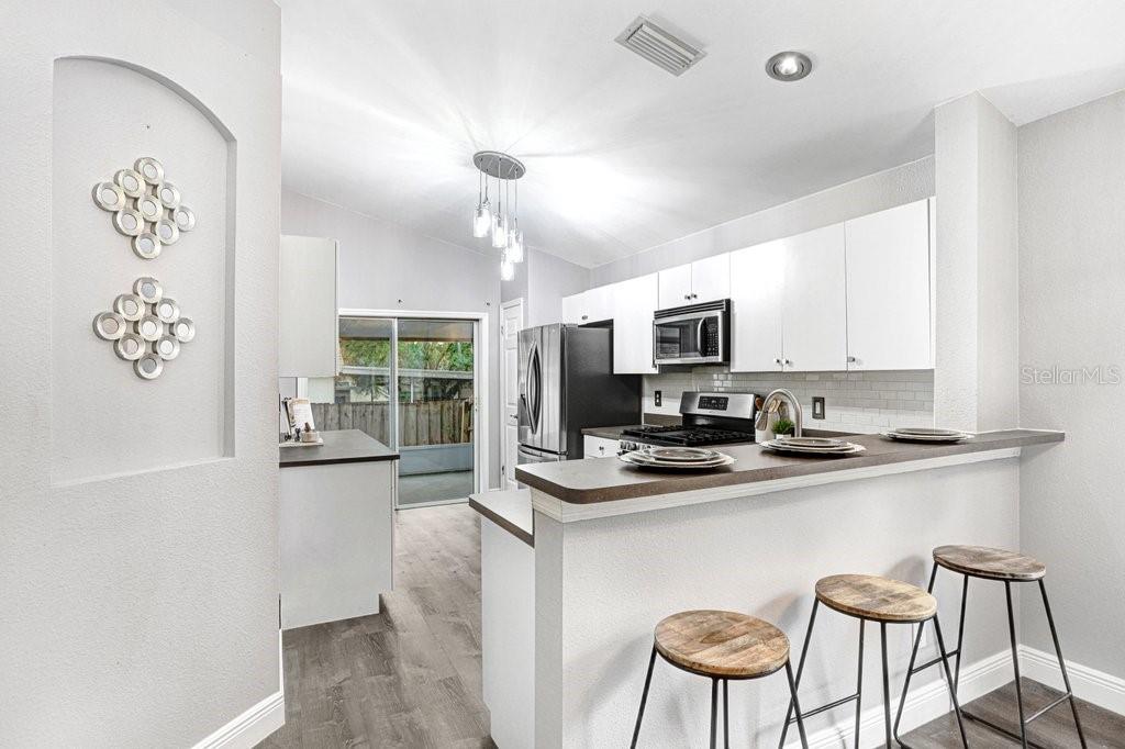 807 Cape Cod Circle Valrico, FL 33594 - Photo 10 of 26 a kitchen with stainless steel appliances granite countertop a stove top oven a sink a dining table and chairs