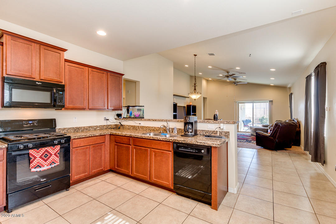 7615 West Carter Road Laveen, AZ 85339 - Photo 5 of 34 a kitchen with stainless steel appliances granite countertop a stove top oven a sink dishwasher a dining table and chairs with wooden floor