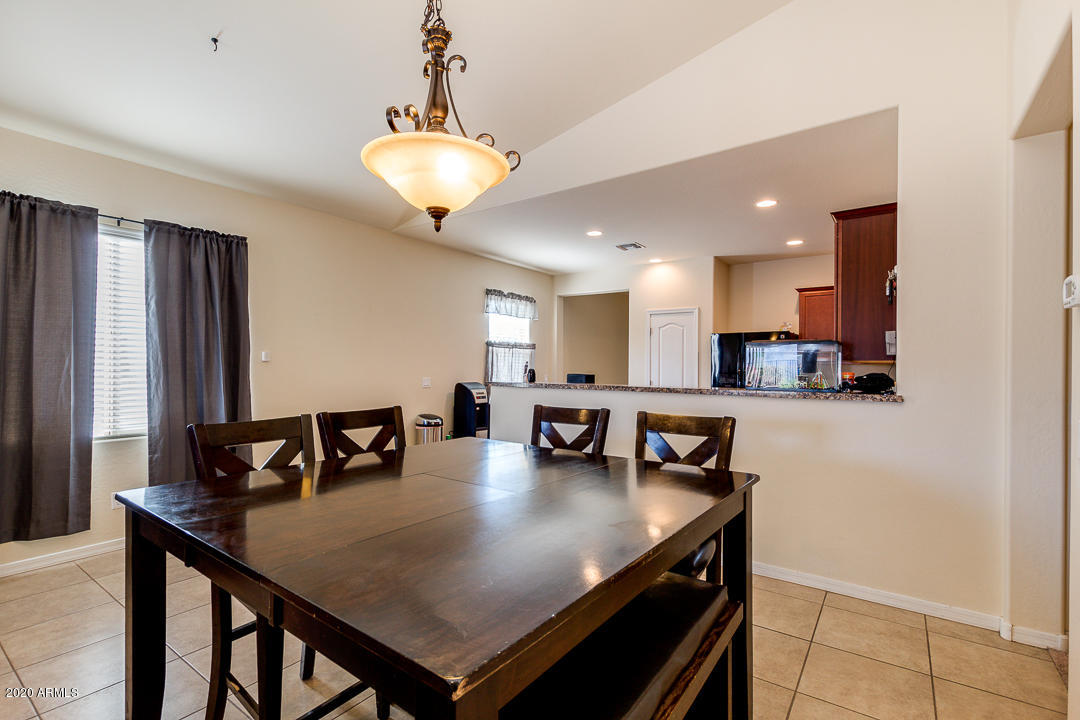 7615 West Carter Road Laveen, AZ 85339 - Photo 7 of 34 a open kitchen with stainless steel appliances granite countertop a stove a refrigerator a kitchen island a dining table and chairs with wooden floor