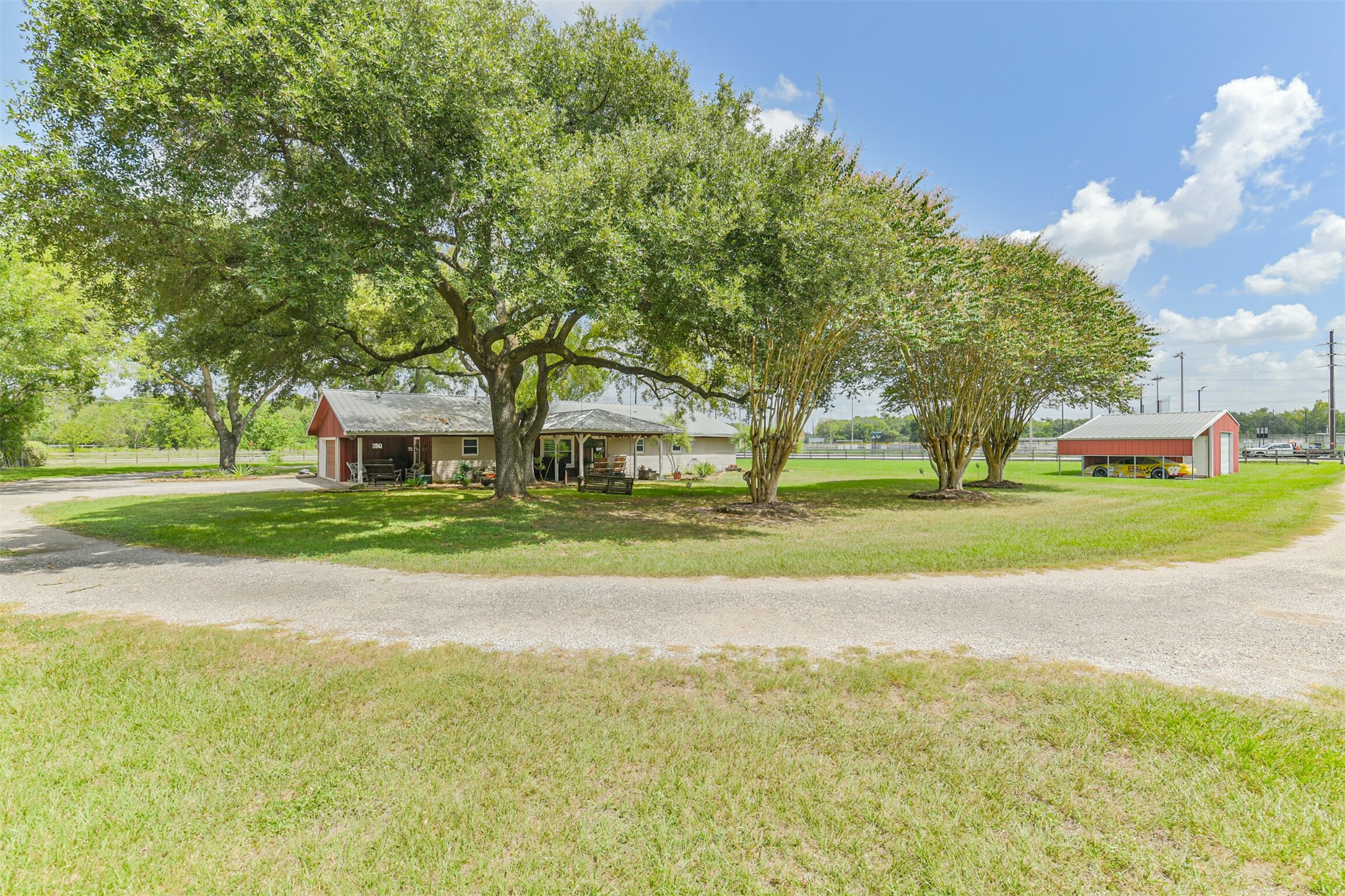 307 West Hufsmith Road Tomball, TX 77375 - Photo 41 of 44 Charming rural property featuring a cozy home surrounded by lush trees and expansive green space, complete with a red barn and circular driveway for easy access.