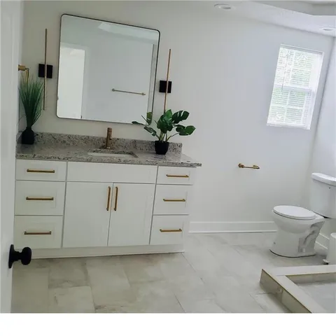 a bathroom with a granite countertop sink a toilet and a mirror