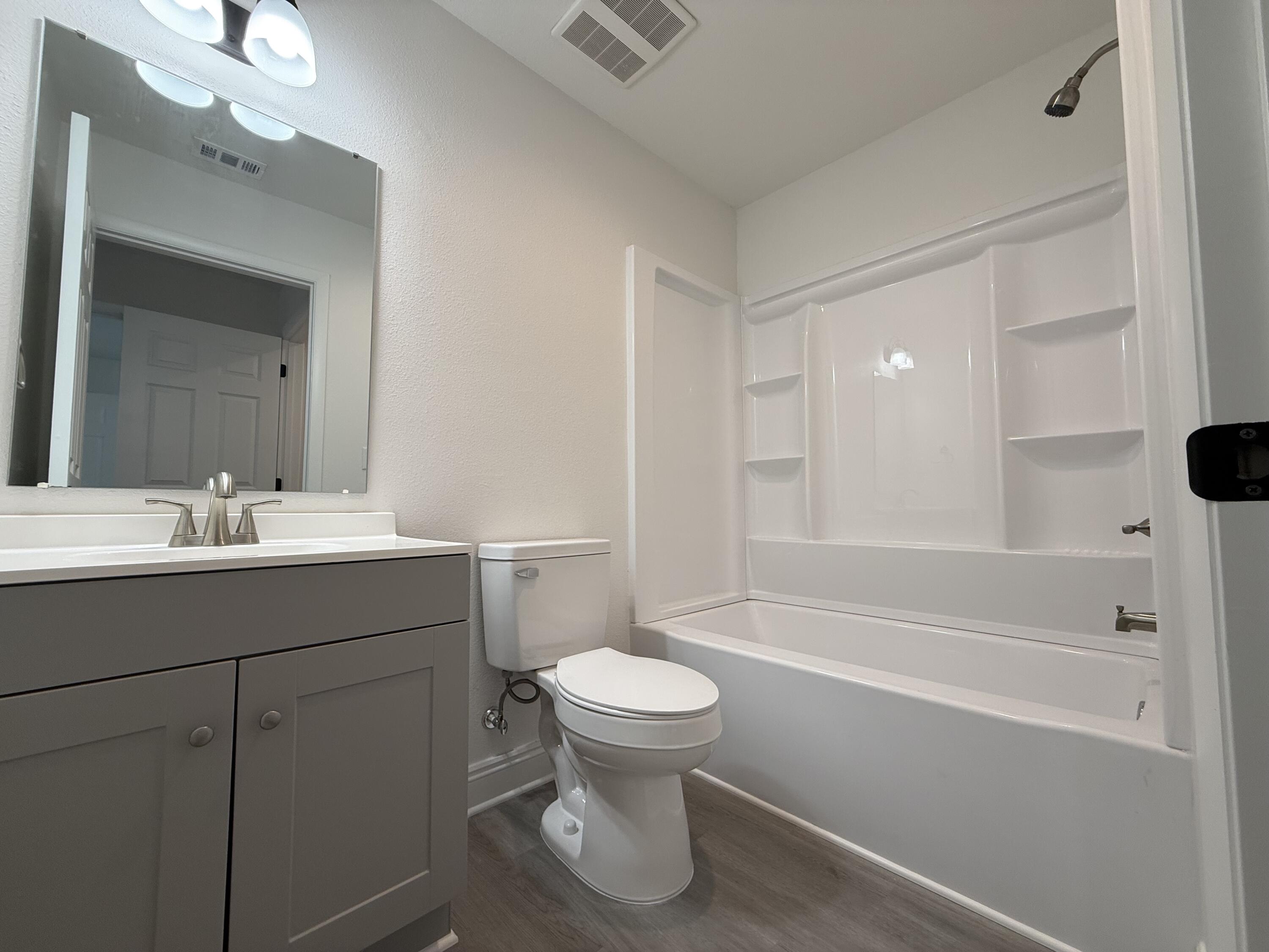 32 Constitution Avenue, Unit AB DeFuniak Springs, FL 32433 - Photo 14 of 22 a bathroom with a bathtub shower sink vanity mirror and toilet